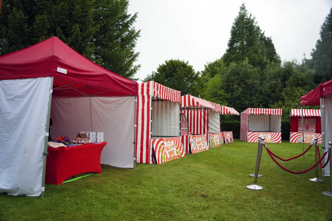 Red-and-white striped catering tents arranged across a lawn.