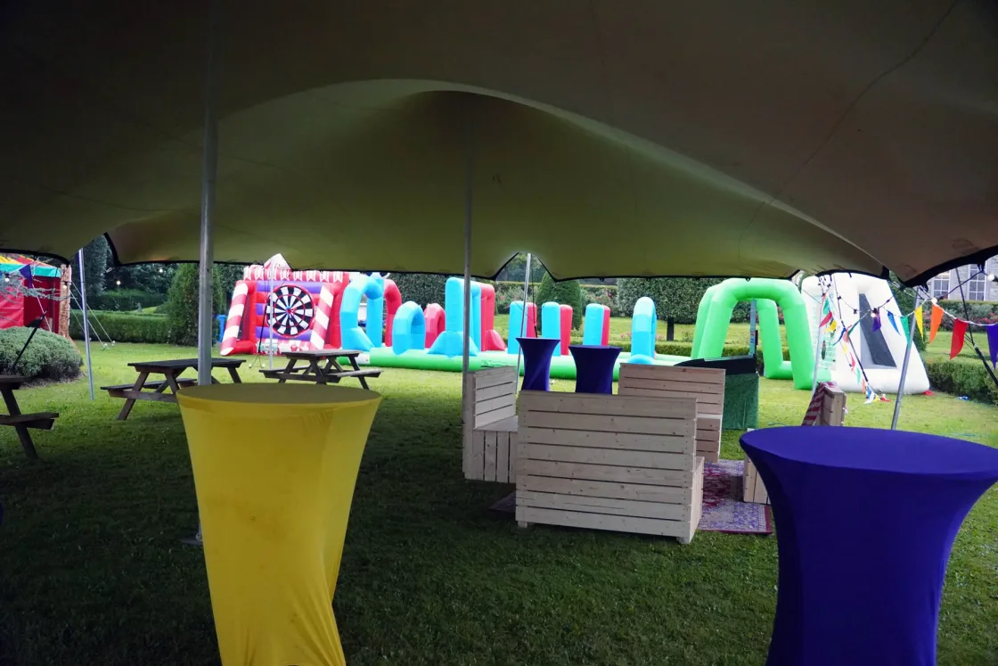 Colourful cocktail tables and outdoor games beneath a large canopy.