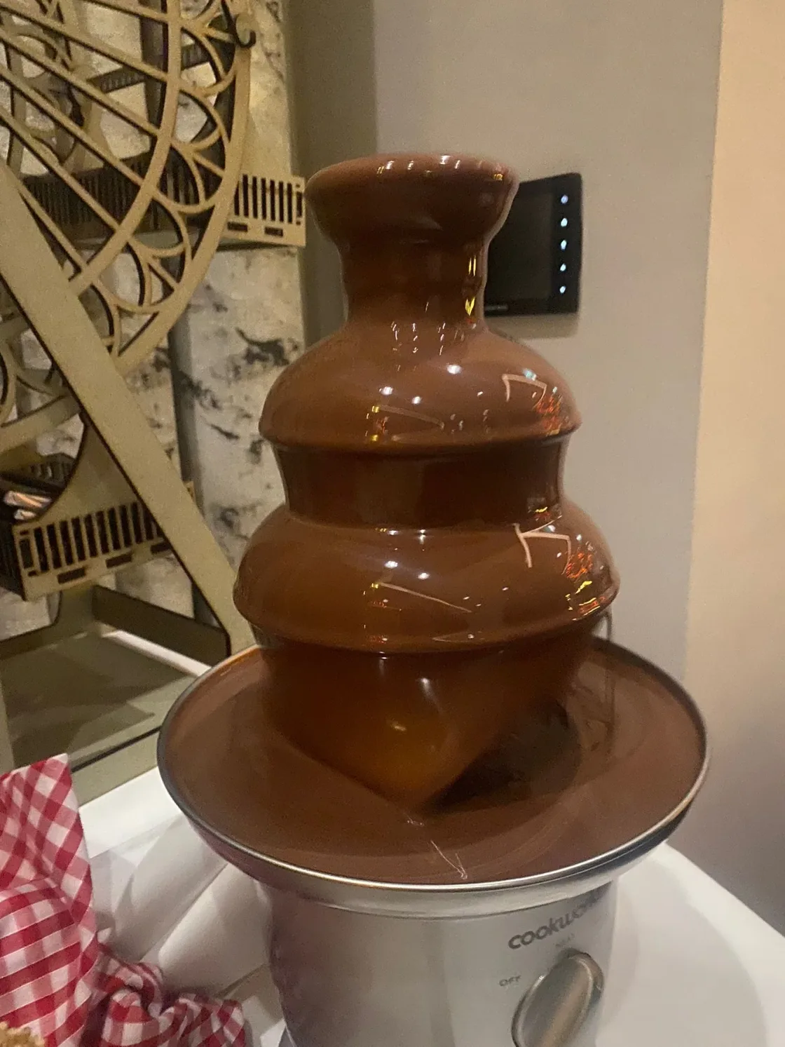 A tiered chocolate fountain on a catering table.