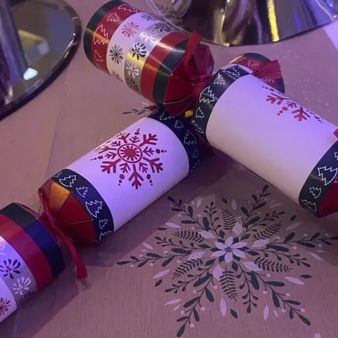 Christmas crackers and snowflake decorations on a dining table.