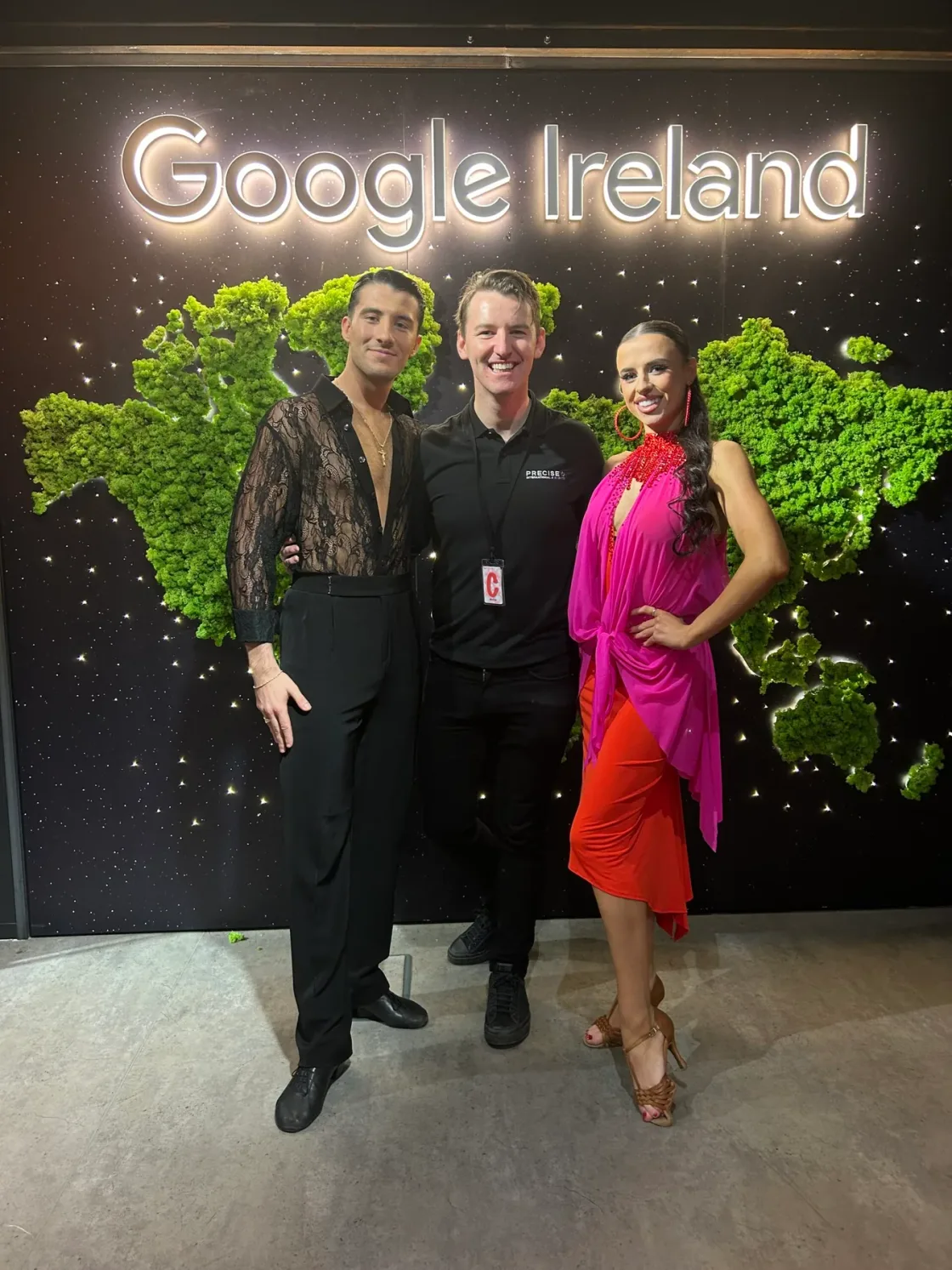 Three guests posing beneath a Google Ireland sign and green wall decoration.