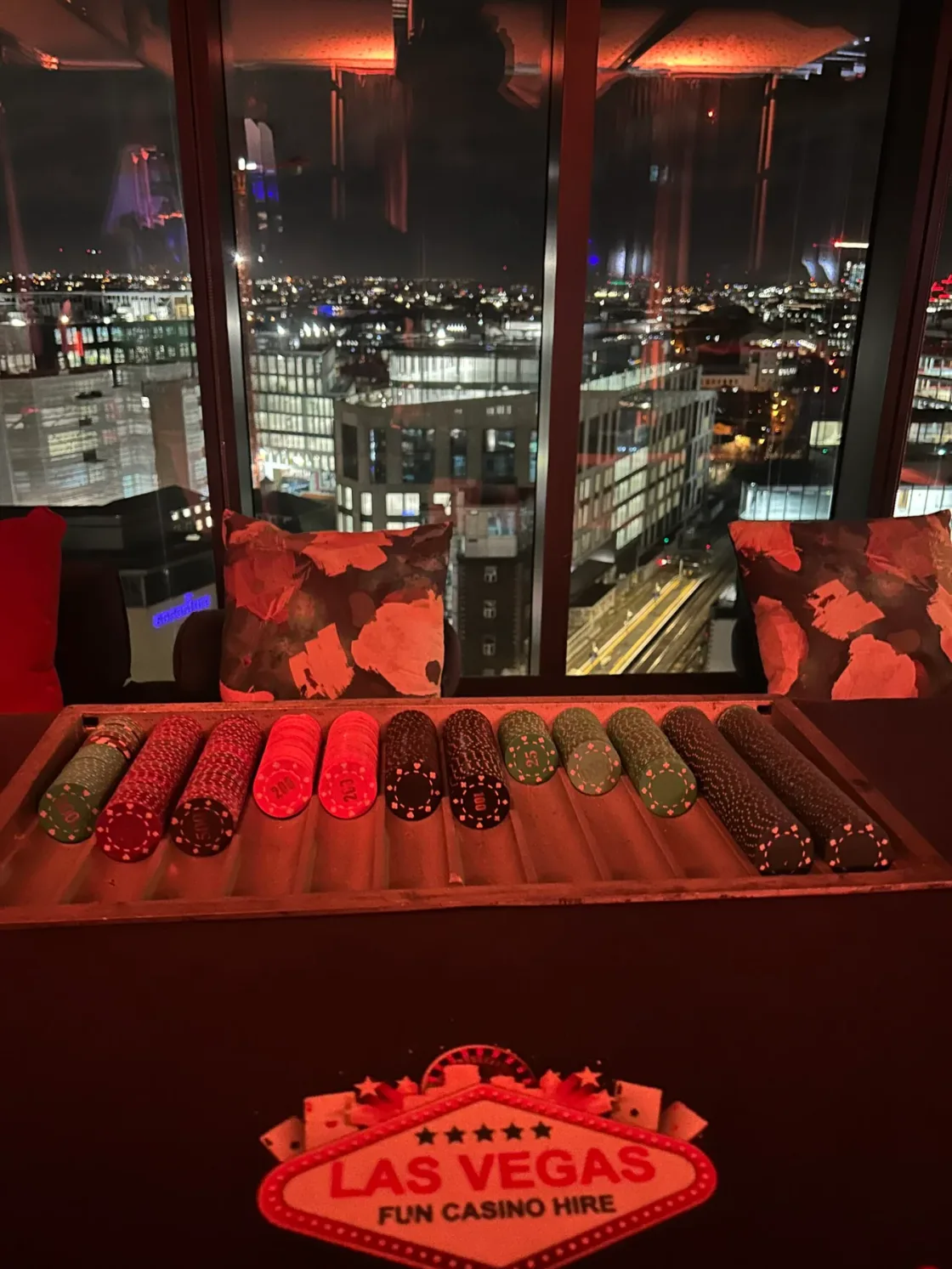 A red Las Vegas-themed display beside windows overlooking the city at night.