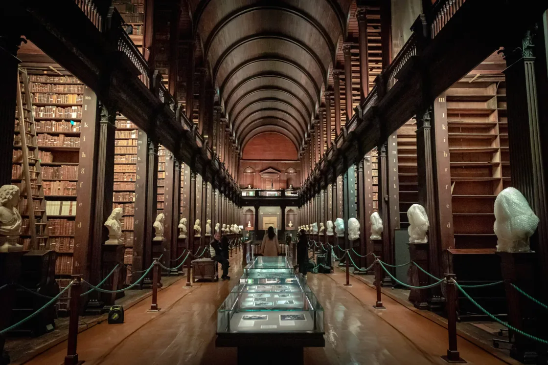 A long vaulted library lined with bookshelves and marble busts.
