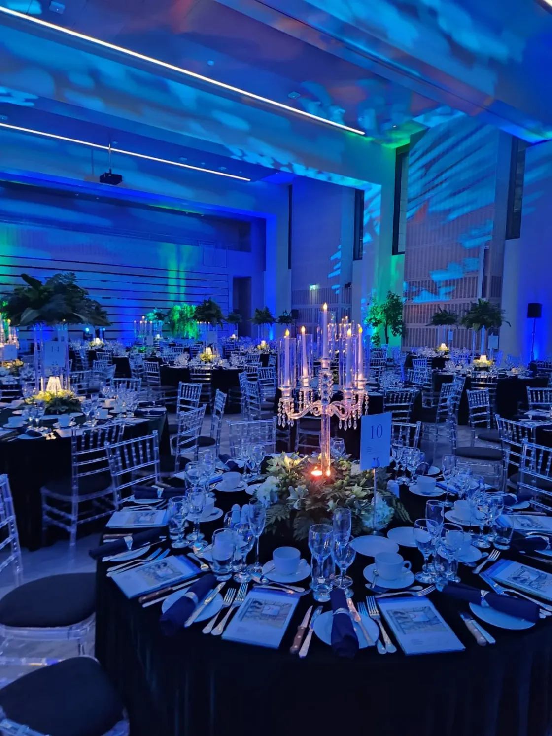 Round dining tables prepared beneath blue lighting and ceiling projections.