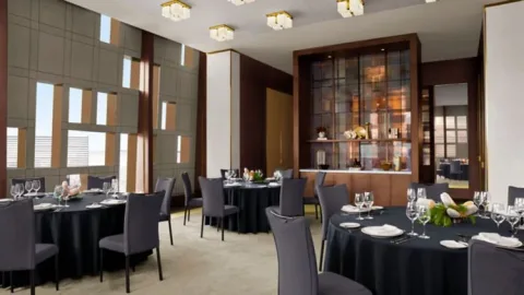 A private dining room with dark table linens and large windows.