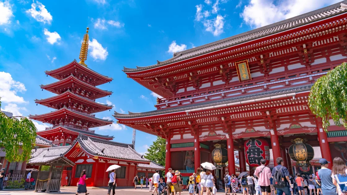 Visitors outside a red temple complex with a pagoda.