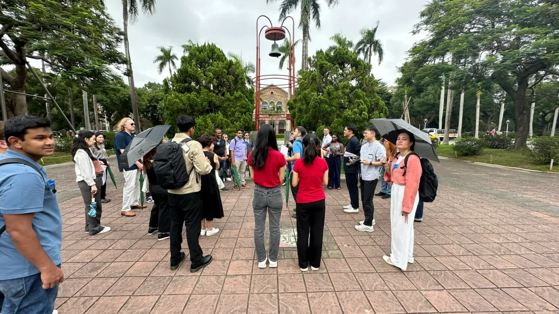 A group gathered beside palm trees in a paved outdoor area.