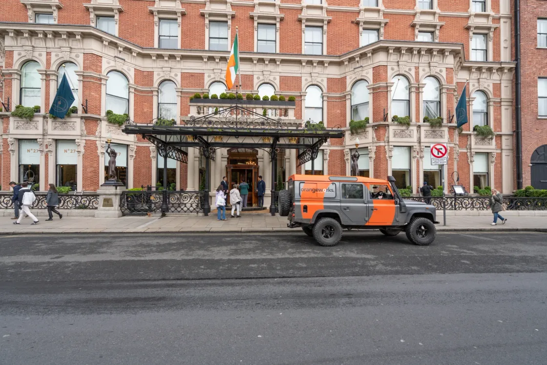 A Land Rover parked outside a red-brick hotel entrance.