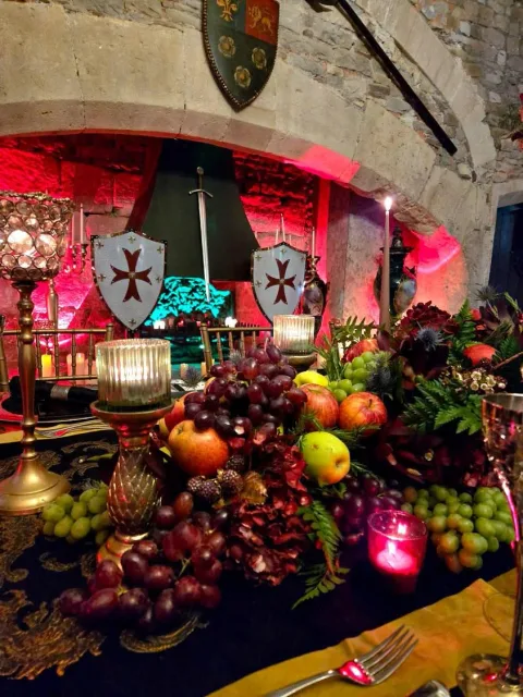 A display of fruit and decorative serving vessels beneath a stone arch.