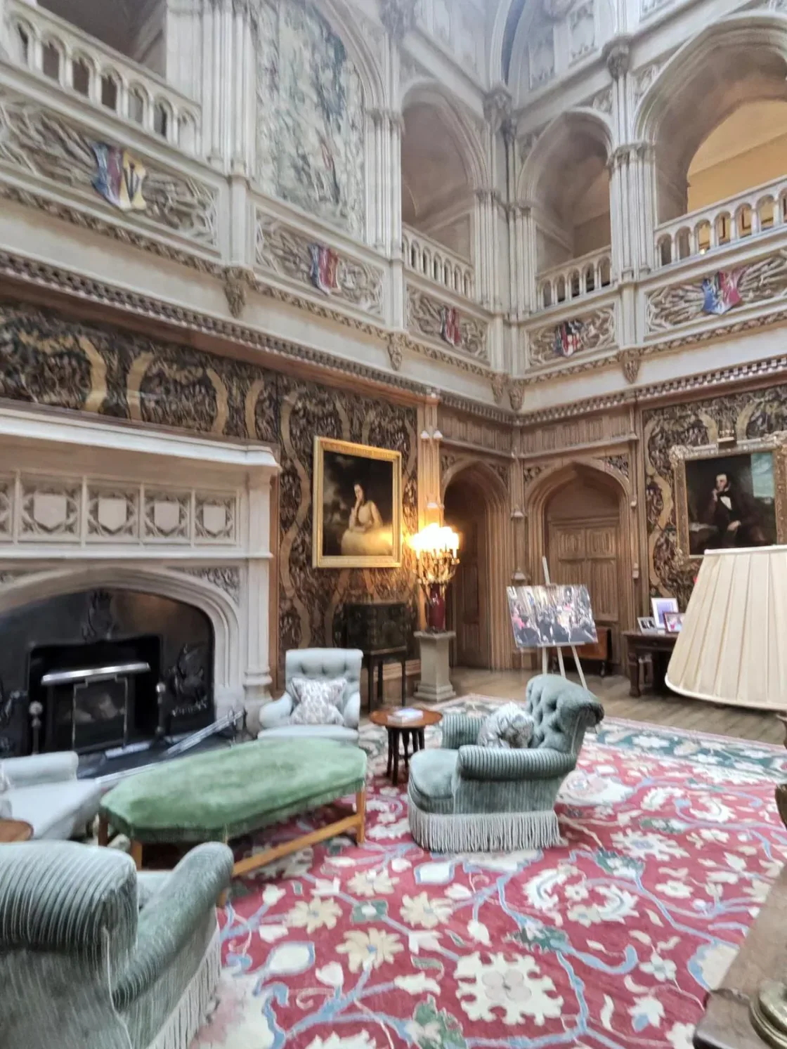 A grand drawing room with galleries, carved stone details and upholstered seating.