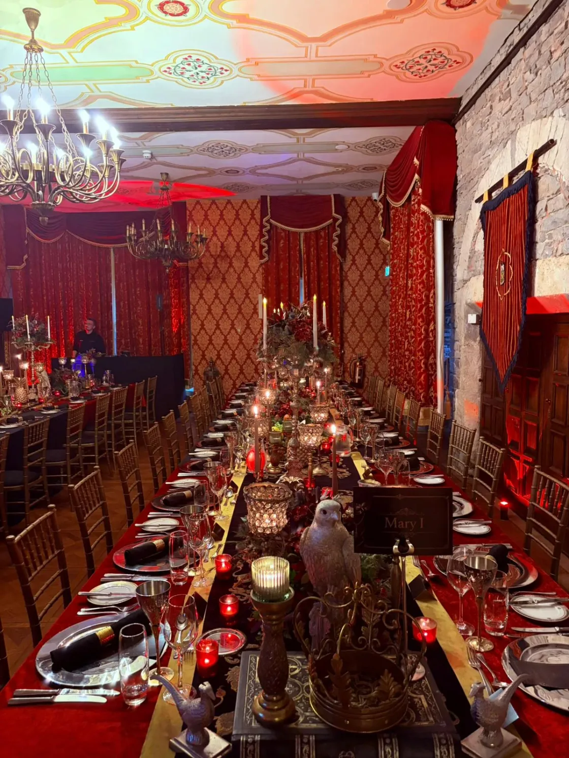 A long banquet table set in a richly decorated red dining room.