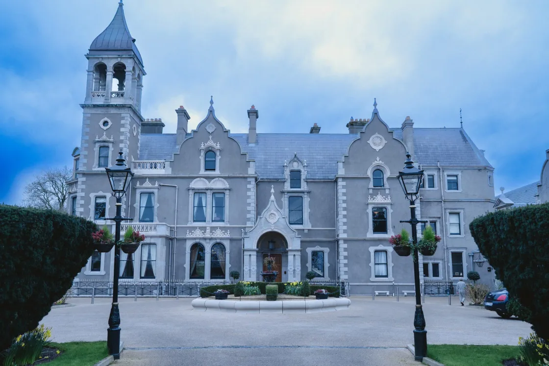 A stone country house with towers and a courtyard entrance.