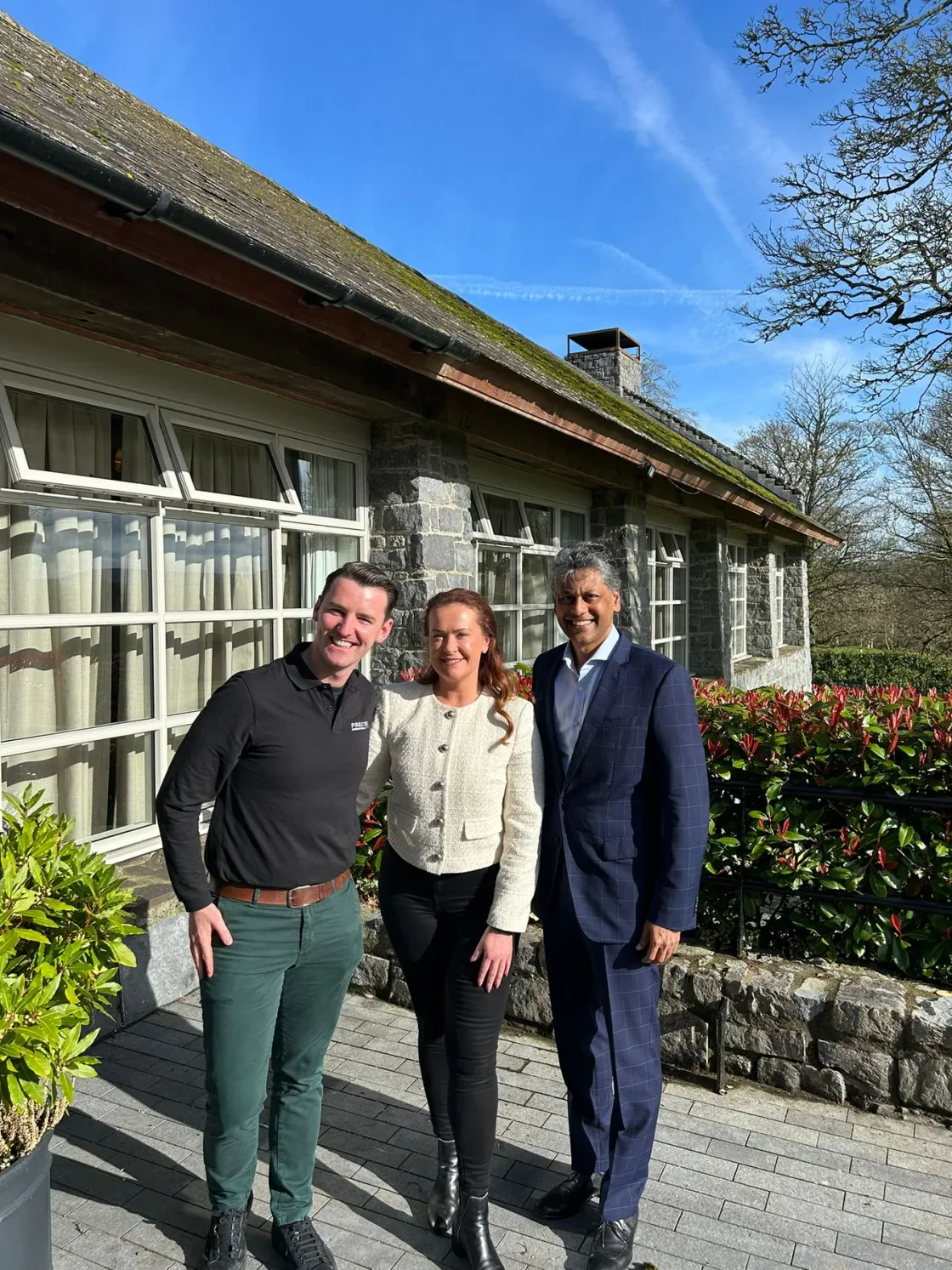 Three guests standing outside a pavilion overlooking the grounds.