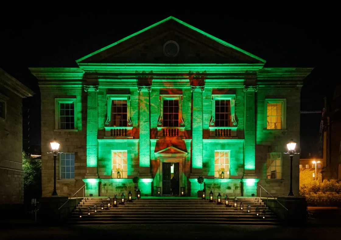 A columned stone building illuminated in green at night.