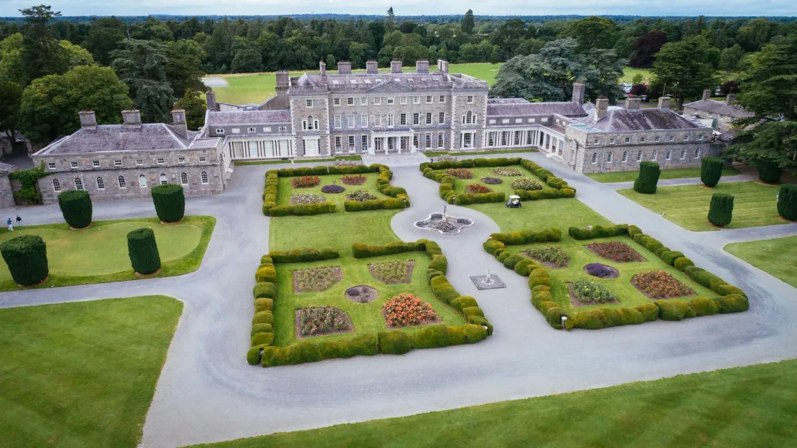 Aerial view of a country house and its symmetrical formal gardens.