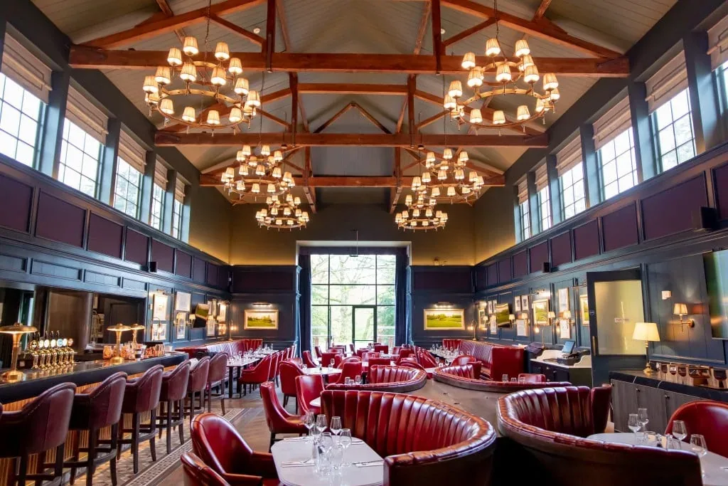 A lounge with red seating, a high timber ceiling and chandeliers.