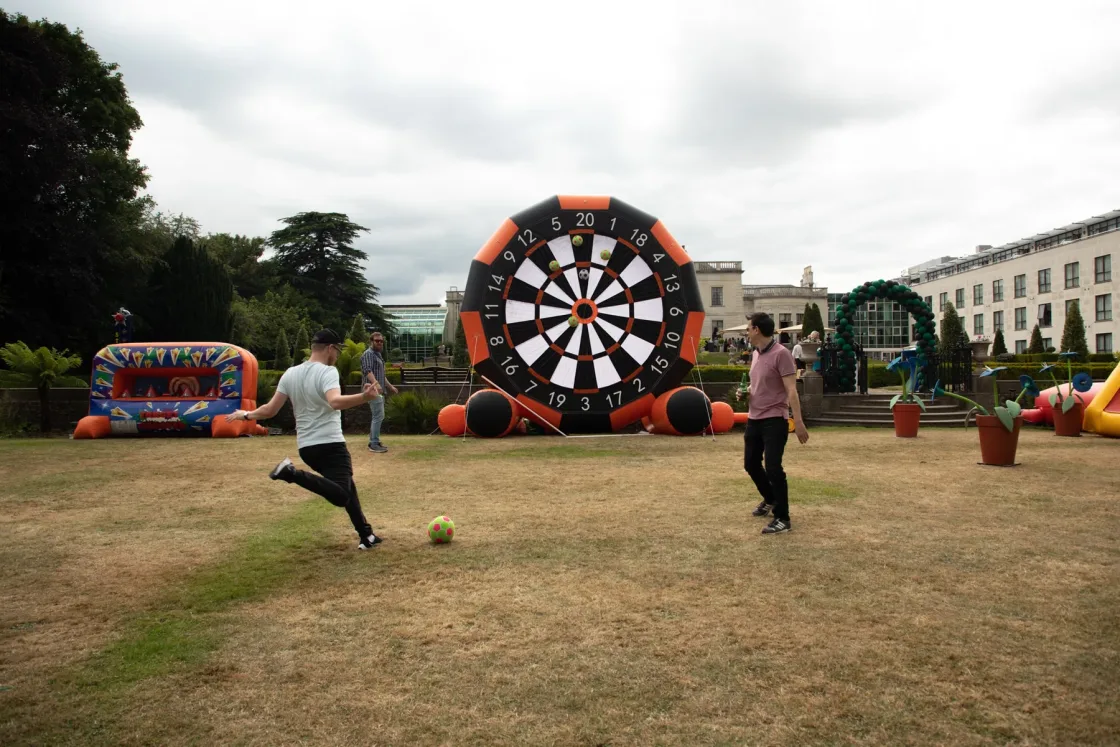 Guests playing football darts on a lawn at an outdoor event.