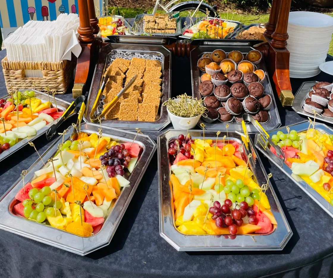 A buffet counter with serving dishes of salad, vegetables and desserts.