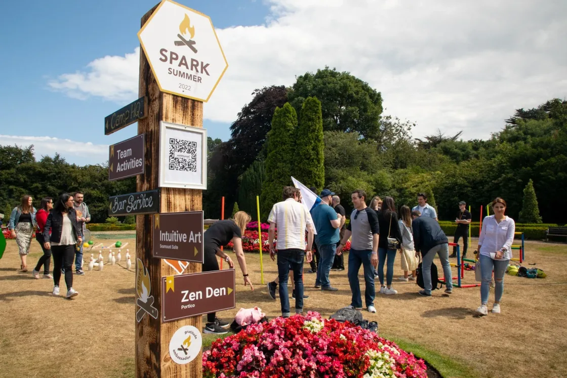 Guests walking past an event sign and a bright pink floral display.