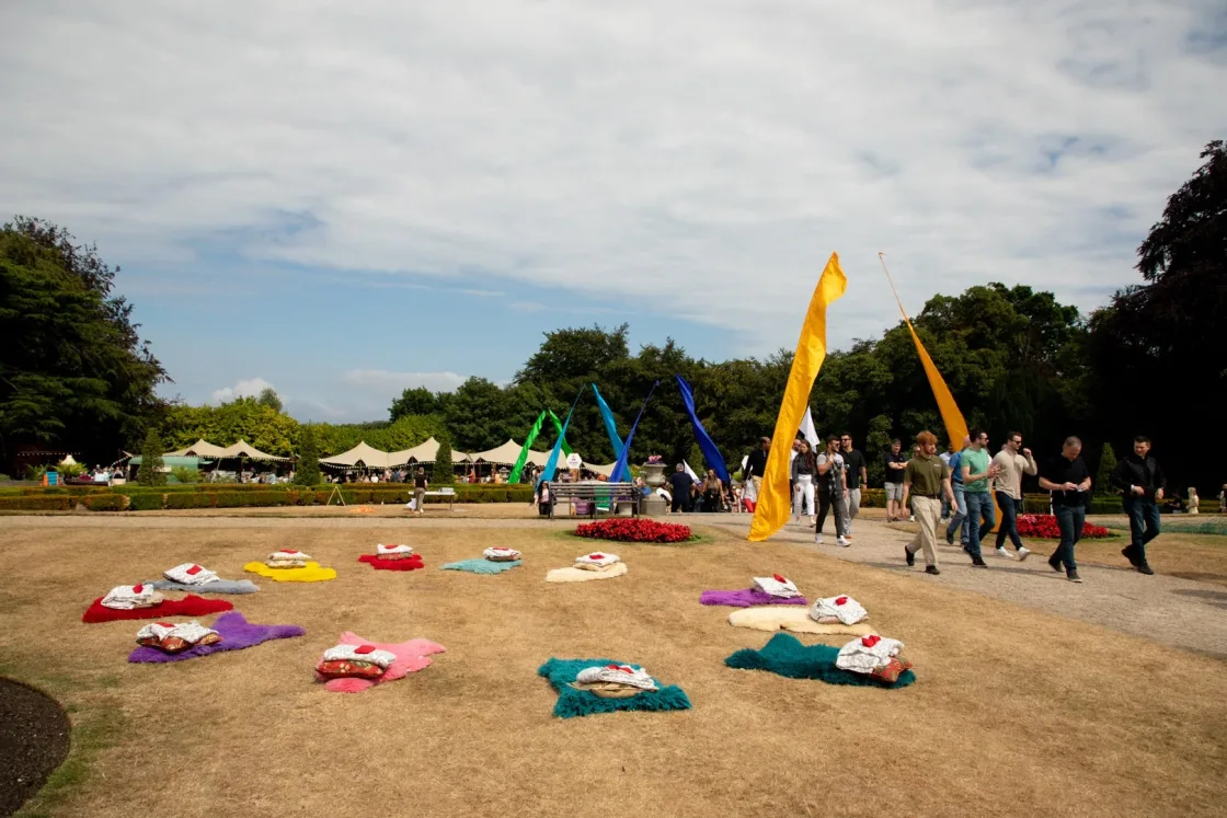 An event lawn laid out with picnic blankets, cushions and activity flags.