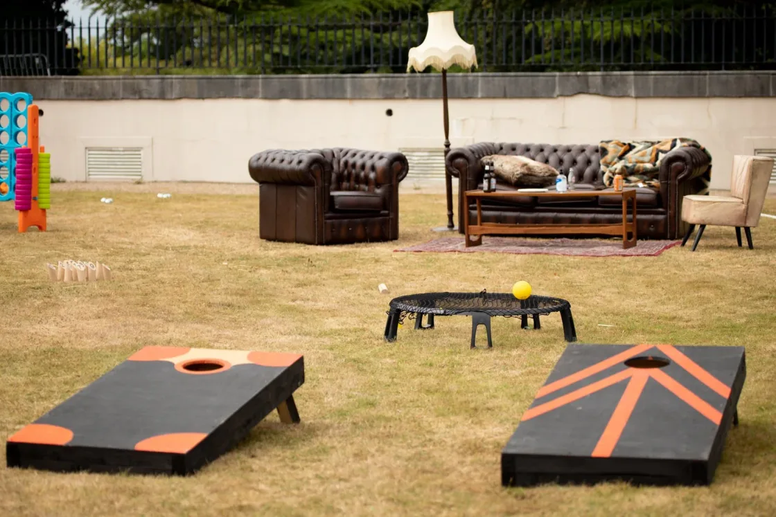Cornhole boards and lounge furniture arranged on a lawn.