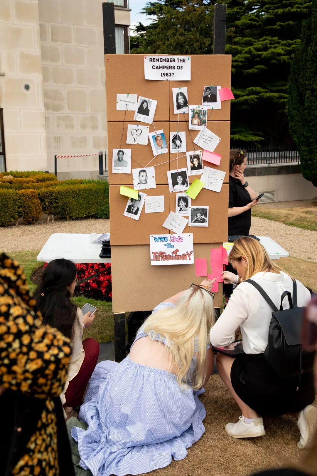 Guests beside a board displaying instant photographs at an outdoor event.
