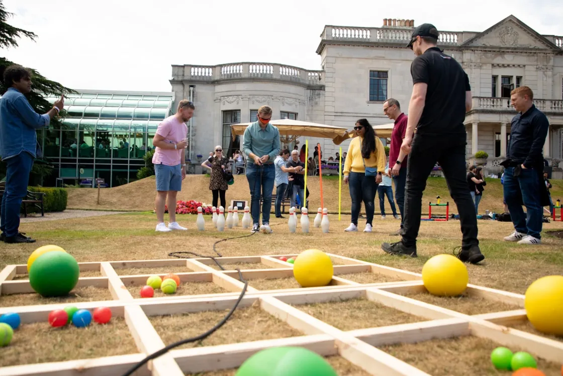 Guests playing a large wooden ball-maze game on a lawn.