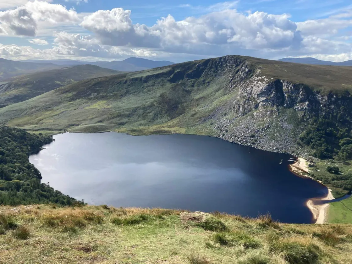 A mountain lake surrounded by open hills and rocky slopes.