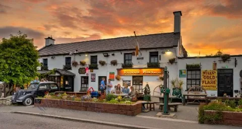 A pub exterior beneath an orange evening sky.