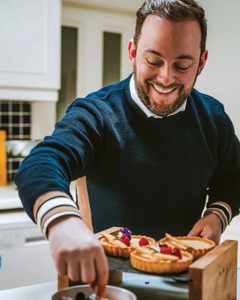 A guest preparing a pizza during a cookery activity.
