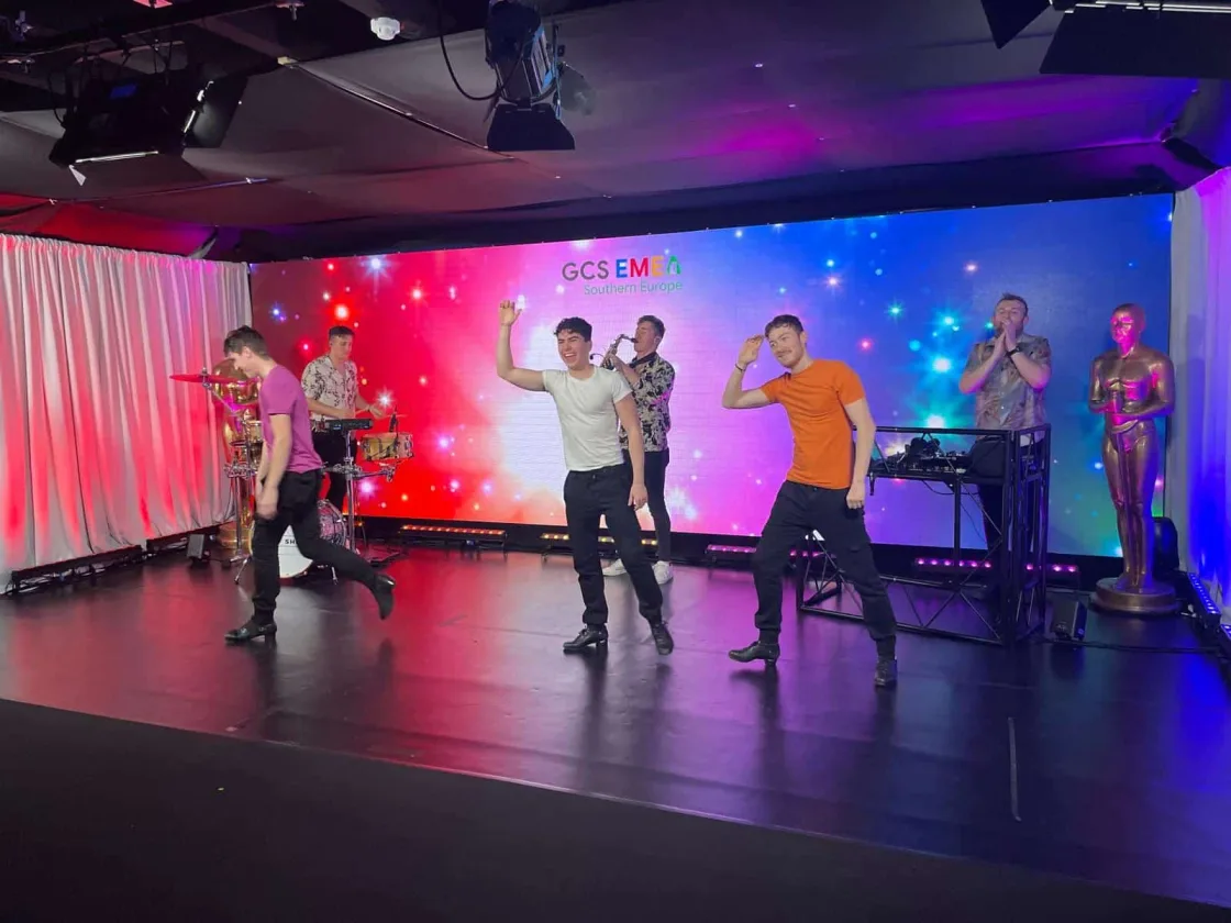Dancers performing together on an indoor event stage.