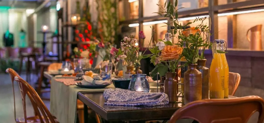 A dining table decorated with colourful glass bottles and flowers.
