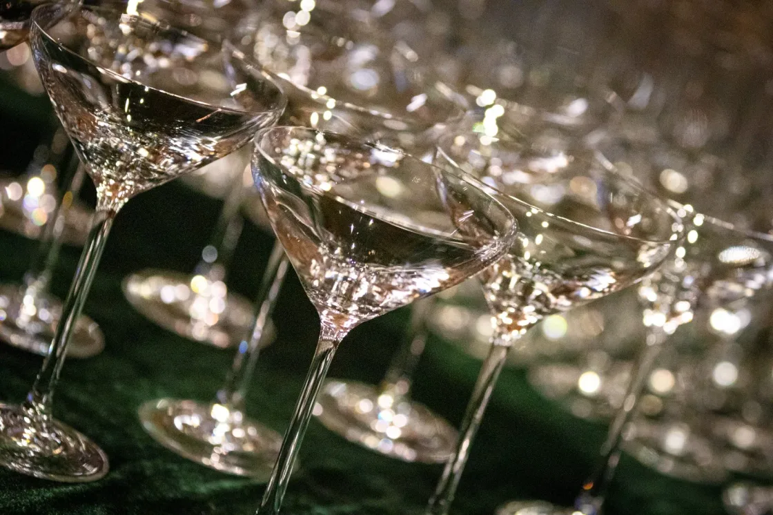 Rows of wine glasses catching the light on a dining table.