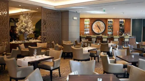 A hotel lounge with dining tables, comfortable chairs and a bar.
