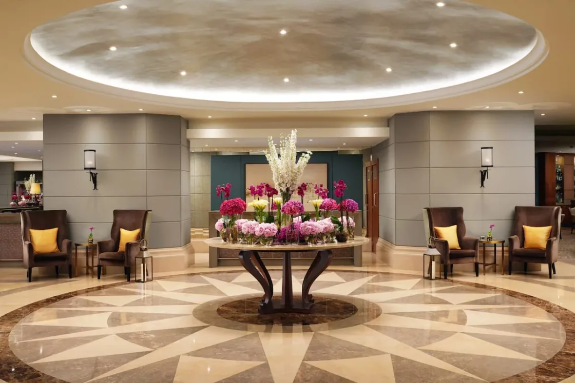 A circular hotel lobby with a floral display beneath a domed ceiling.