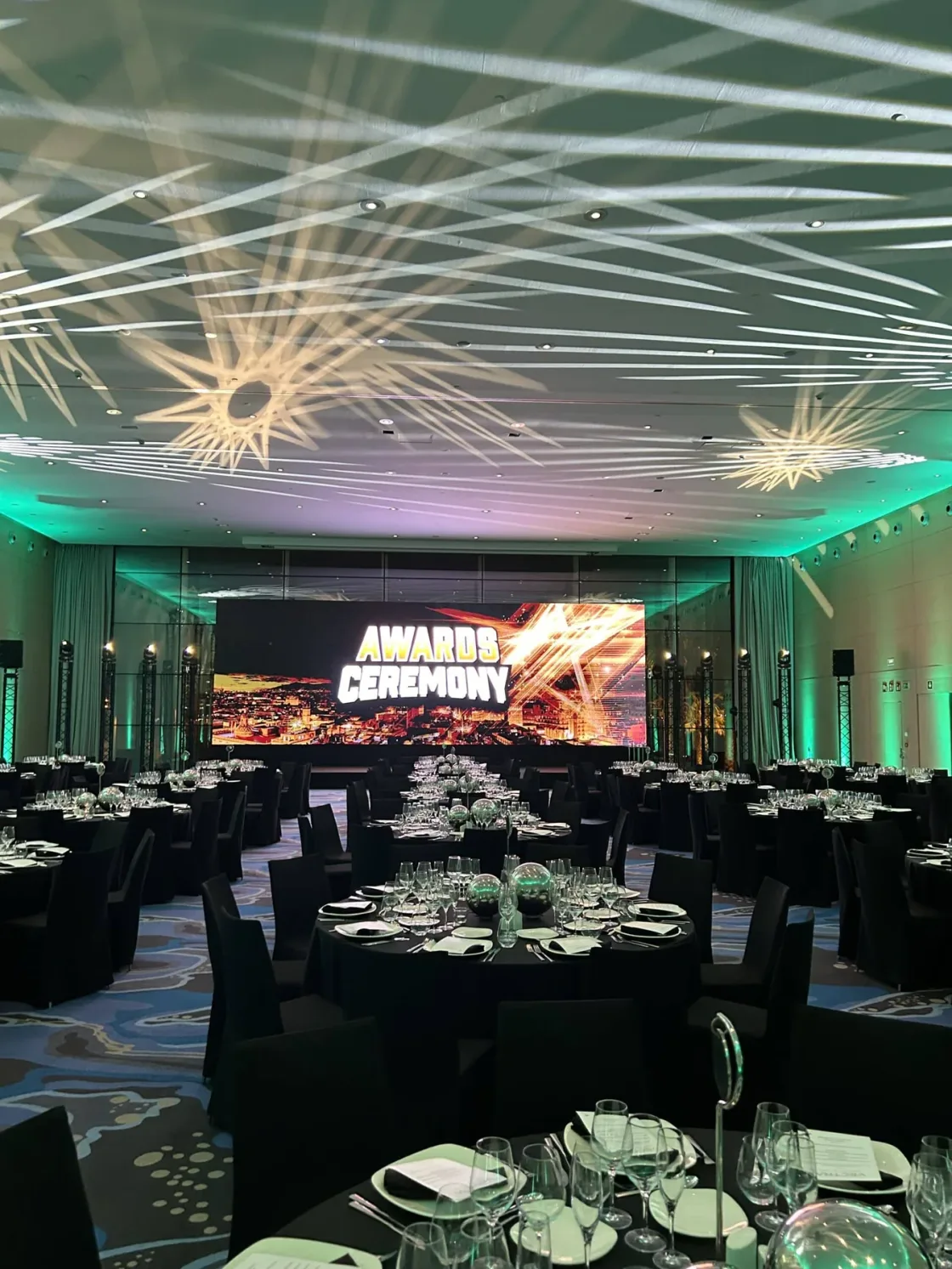 Round dining tables beneath geometric ceiling-light projections.
