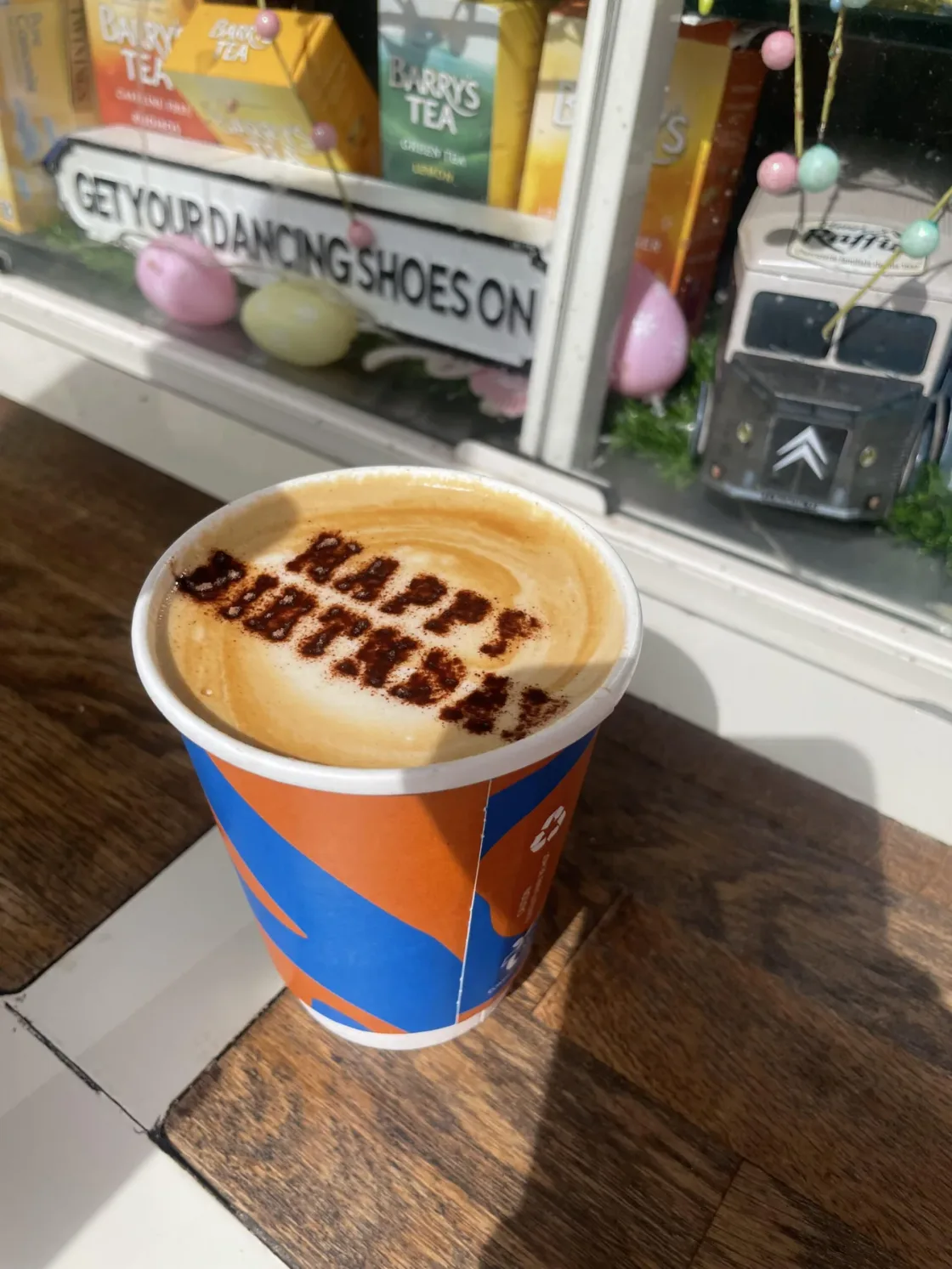 A takeaway coffee with a stencilled design on its foam.