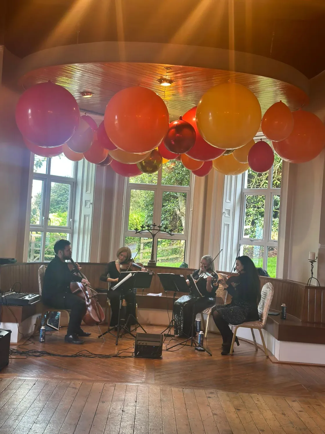 Musicians performing beneath clusters of colourful balloons.
