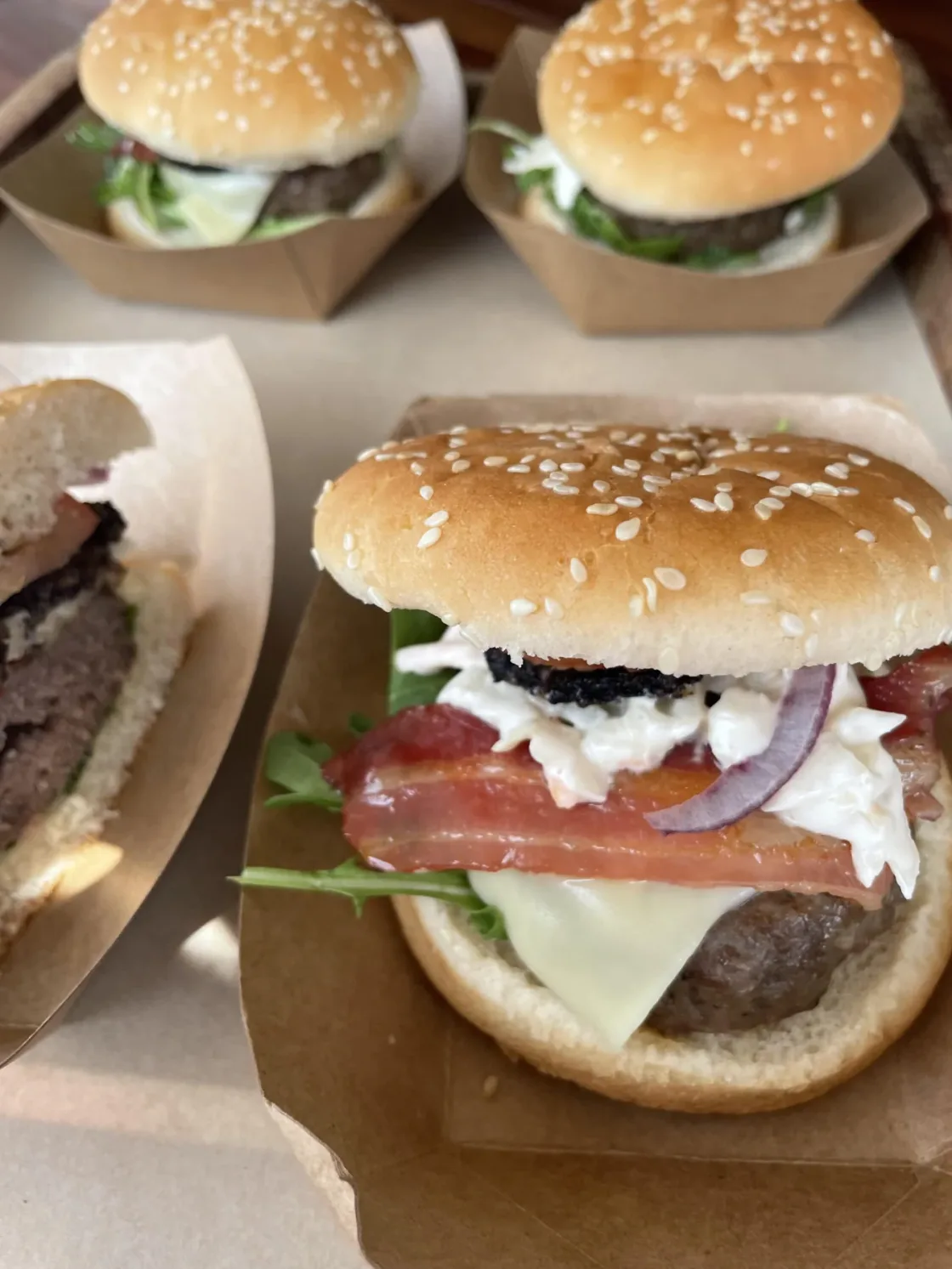 Freshly prepared burgers in paper trays.