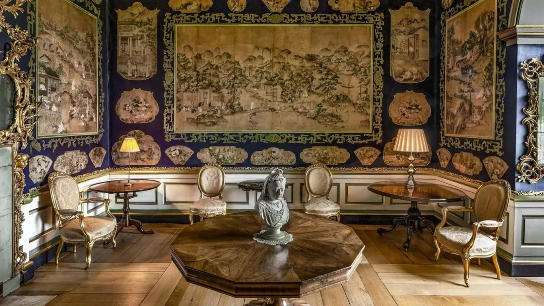 An ornate sitting room with large tapestries and decorative furniture.