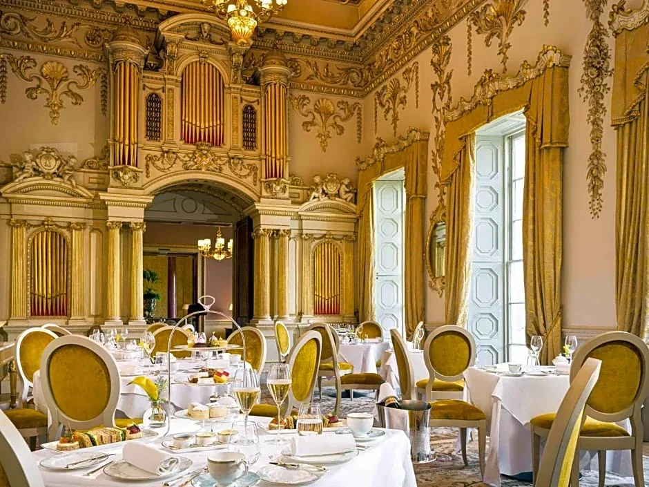 A formal dining table set in an ornate gold-decorated room.