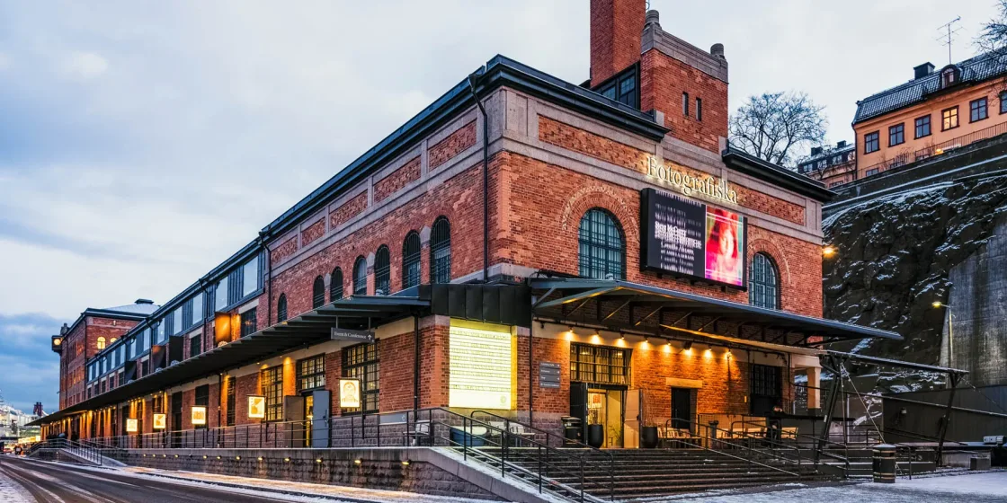 A red-brick venue with tall windows and illuminated street-level entrances.