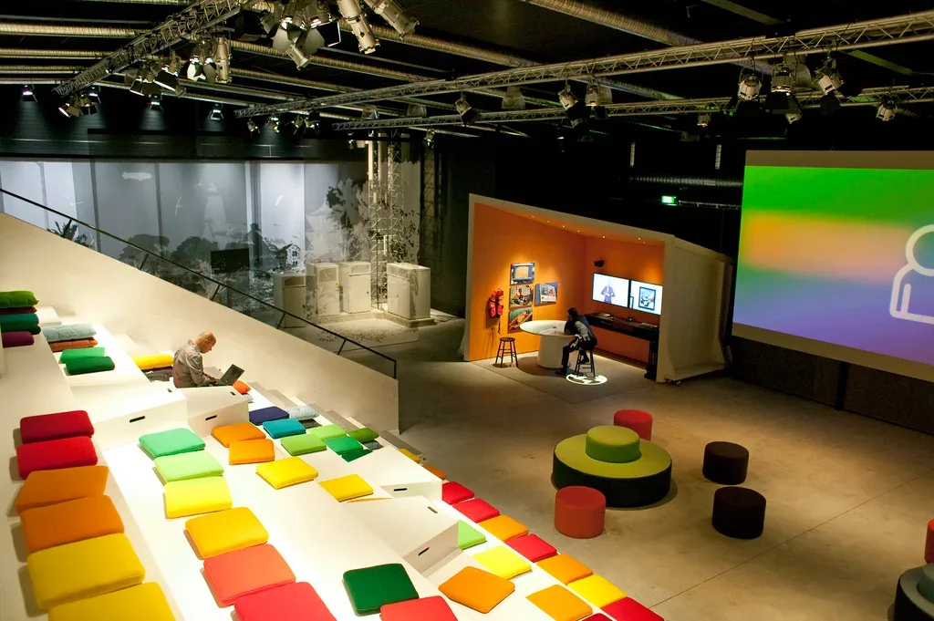 Tiered seating with brightly coloured cushions facing an indoor presentation area.