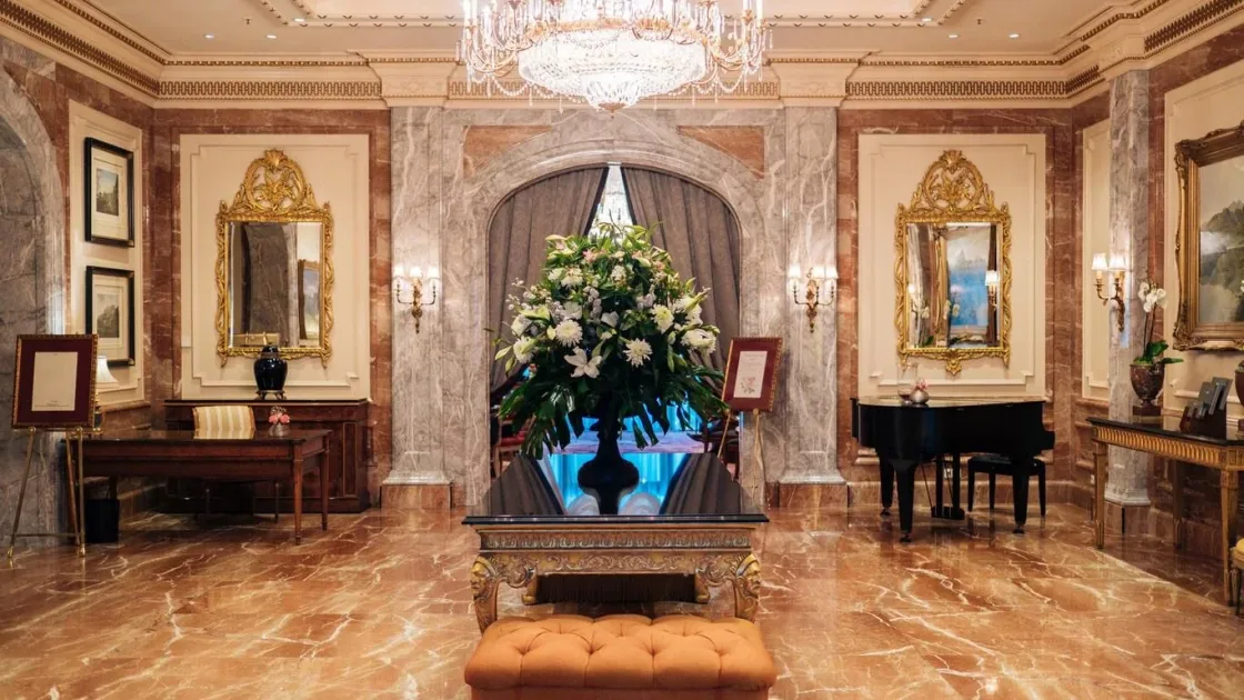 An ornate hotel lobby with chandeliers and a large floral arrangement.