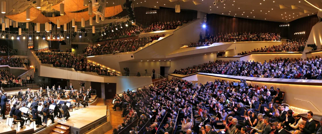 A large seated audience inside a tiered concert hall.
