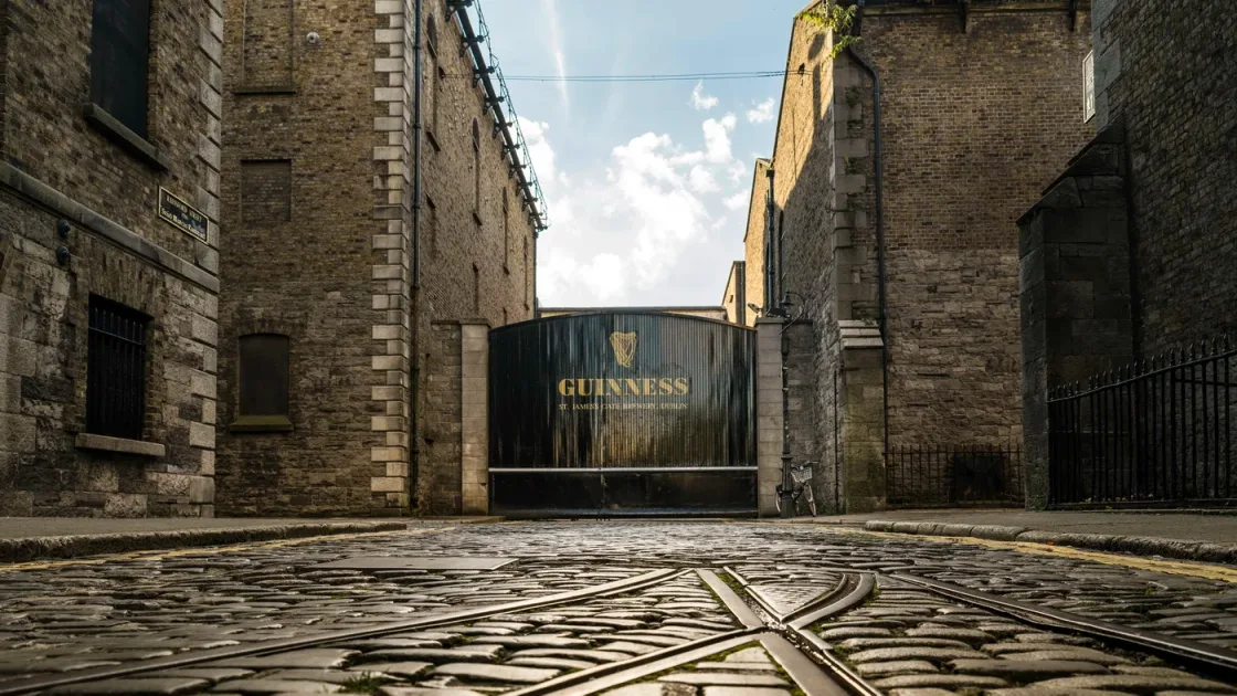 A cobbled lane between tall stone buildings leading to the Guinness entrance.