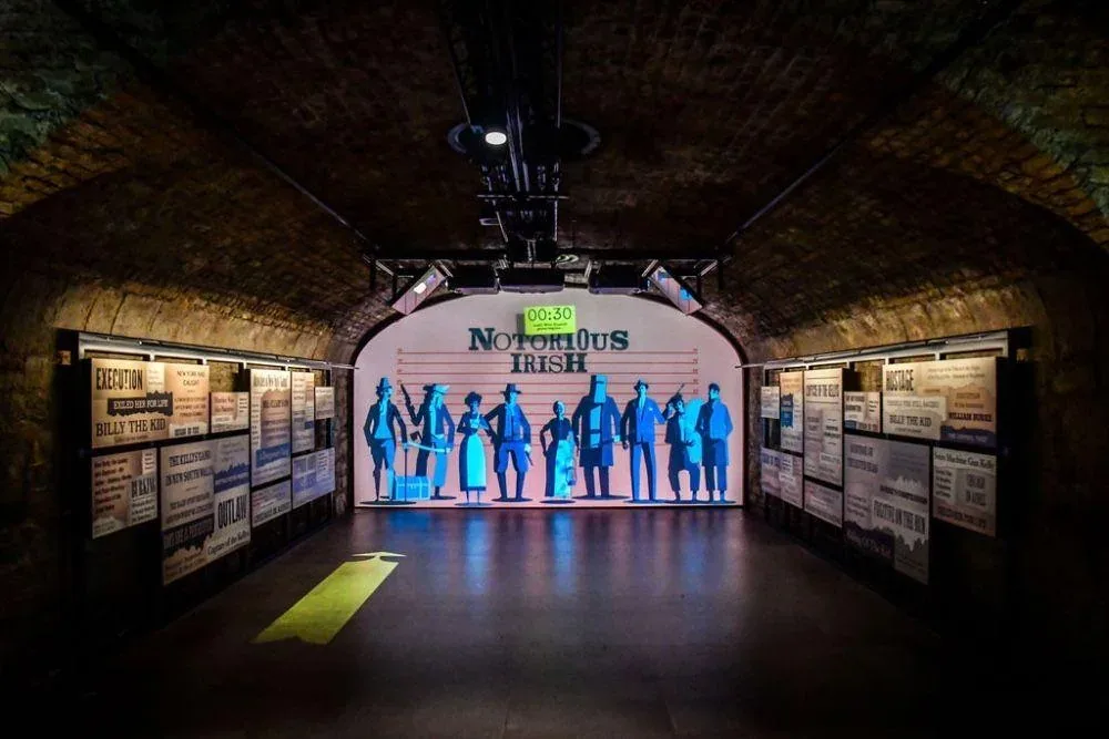 A brick-vaulted exhibition corridor with illuminated display panels.