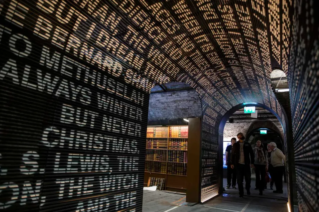 Names projected across the walls and ceiling of a brick-vaulted corridor.