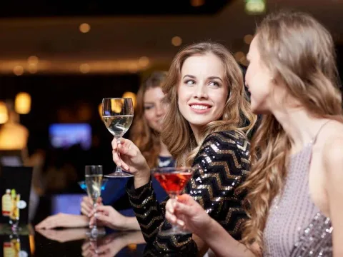 Guests holding drinks and chatting at a bar.