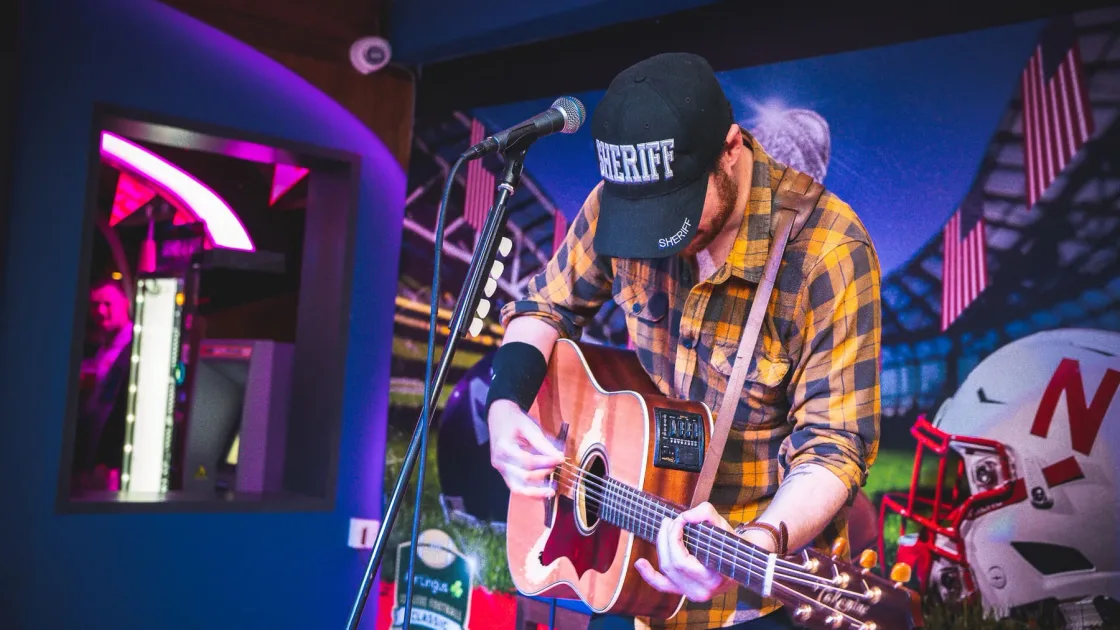 A guitarist performing on a small stage under coloured lights.